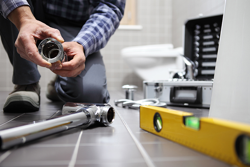 Loodgieter aan het werk in een badkamer, legt de laatste hand aan montage en installatie van gerenoveerde badkamer