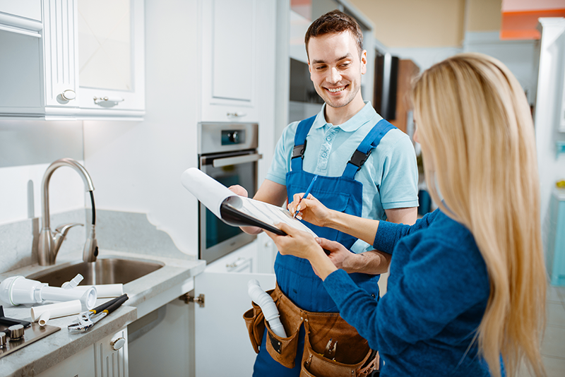 Loodgieter en klant in de keuken met contract. Transparant vooraf.